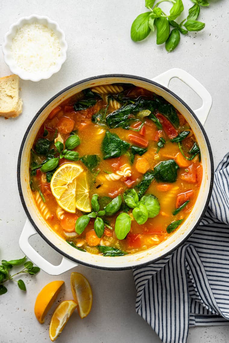 This hearty vegetable stew is packed with nutrients thanks to carrots, onion, and tomatoes, plus pasta and white beans for a satisfying meal. Overhead view of pot of vegetable stew with lemon wedges