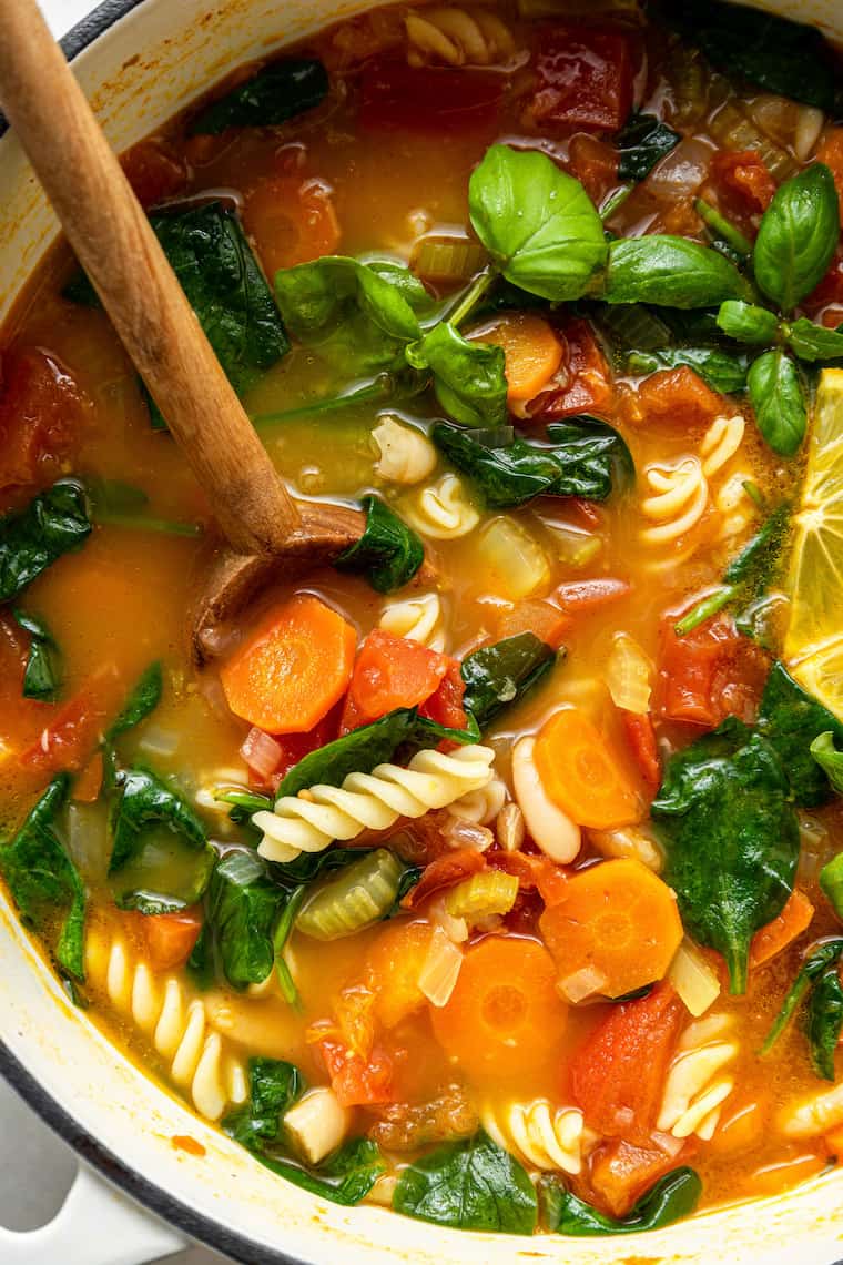 pot of pasta and vegetable stew with basil for garnish