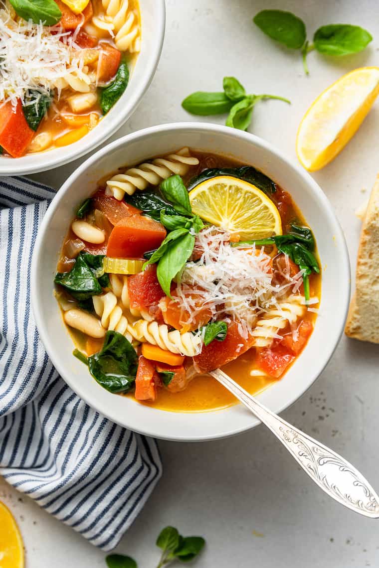 This hearty vegetable stew is packed with nutrients thanks to carrots, onion, and tomatoes, plus pasta and white beans for a satisfying meal. Overhead view of bowl of hearty vegetable stew with parmesan