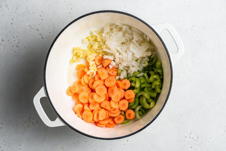 This hearty vegetable stew is packed with nutrients thanks to carrots, onion, and tomatoes, plus pasta and white beans for a satisfying meal. Overhead view of pot with vegetables for stew