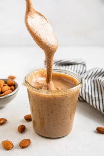 pouring almond butter into a glass jar