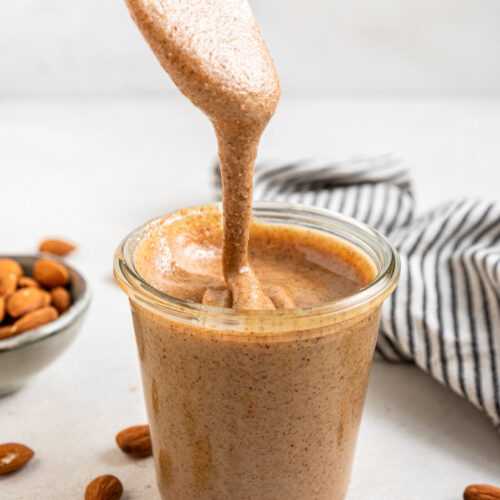 pouring almond butter into a glass jar