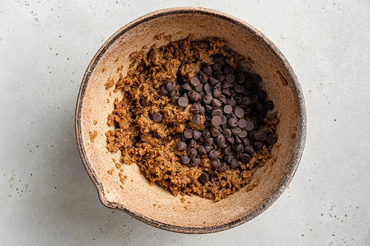 adding chocoalte chips to cookie dough in a bowl