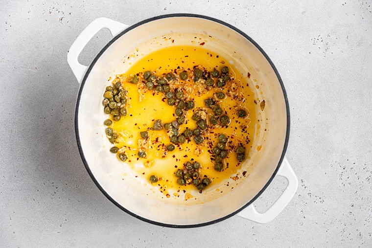 pot of cooking capers and red pepper flakes in oil