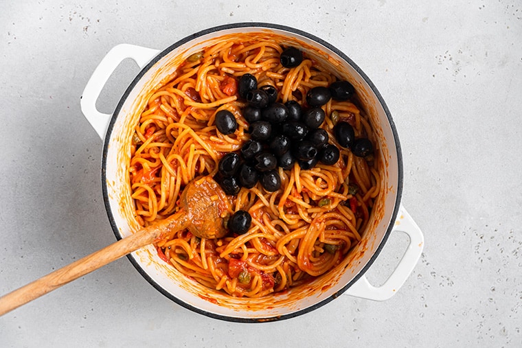 stirring olives into one pot spahgetti