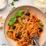 bowl of pasta puttanesca with olives and basil