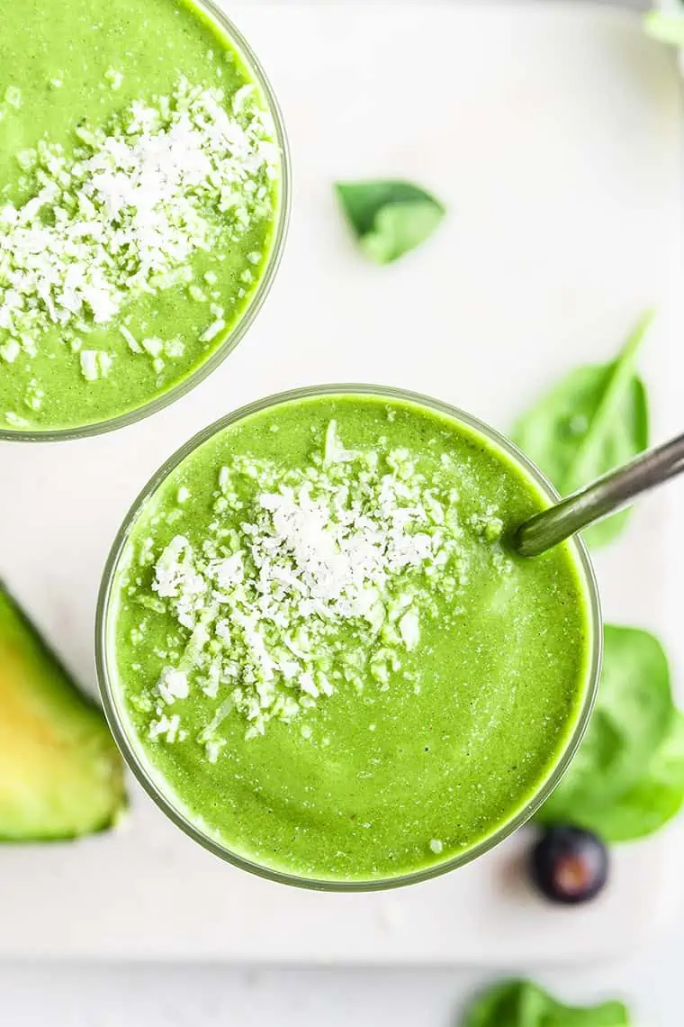 Overhead view of green smoothie in glass topped with shredded coconut