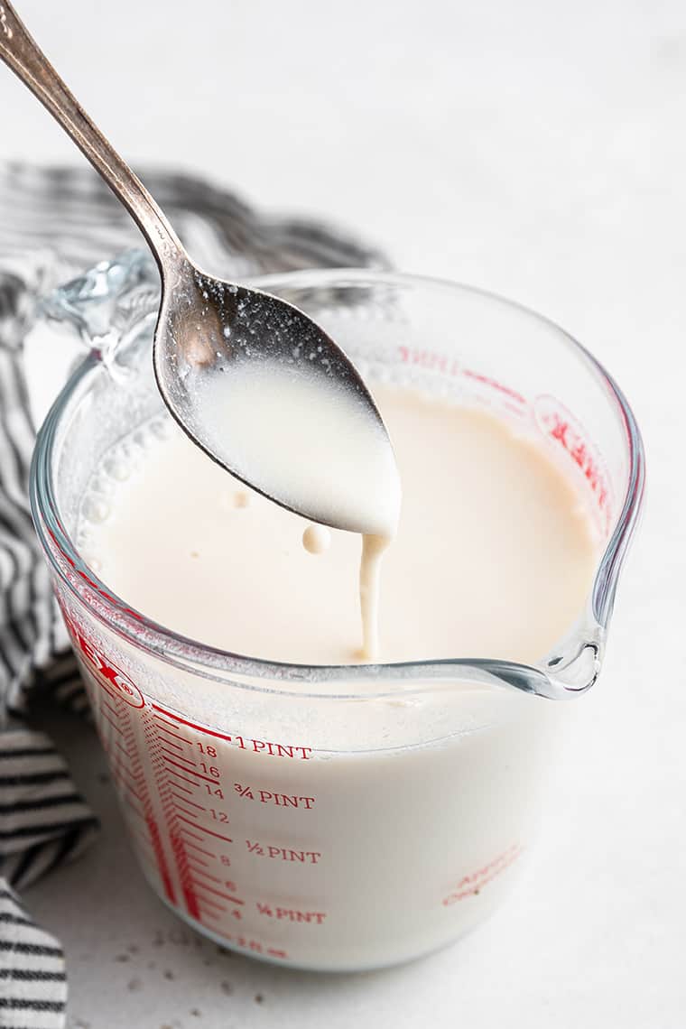 spoon of vegan buttermilk in a measuring cup