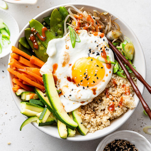 Bowl of quinoa bibimbap with steamed veggies and sunny side up egg
