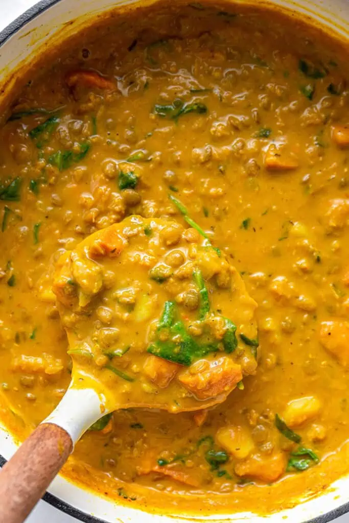 Ladle of detox turmeric lentil soup held over pot