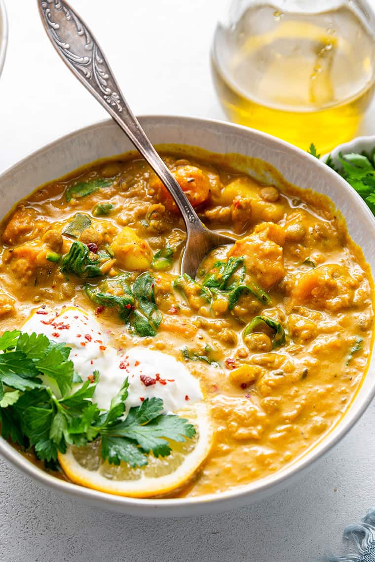 Detox turmeric lentil soup in white bowl with spoon