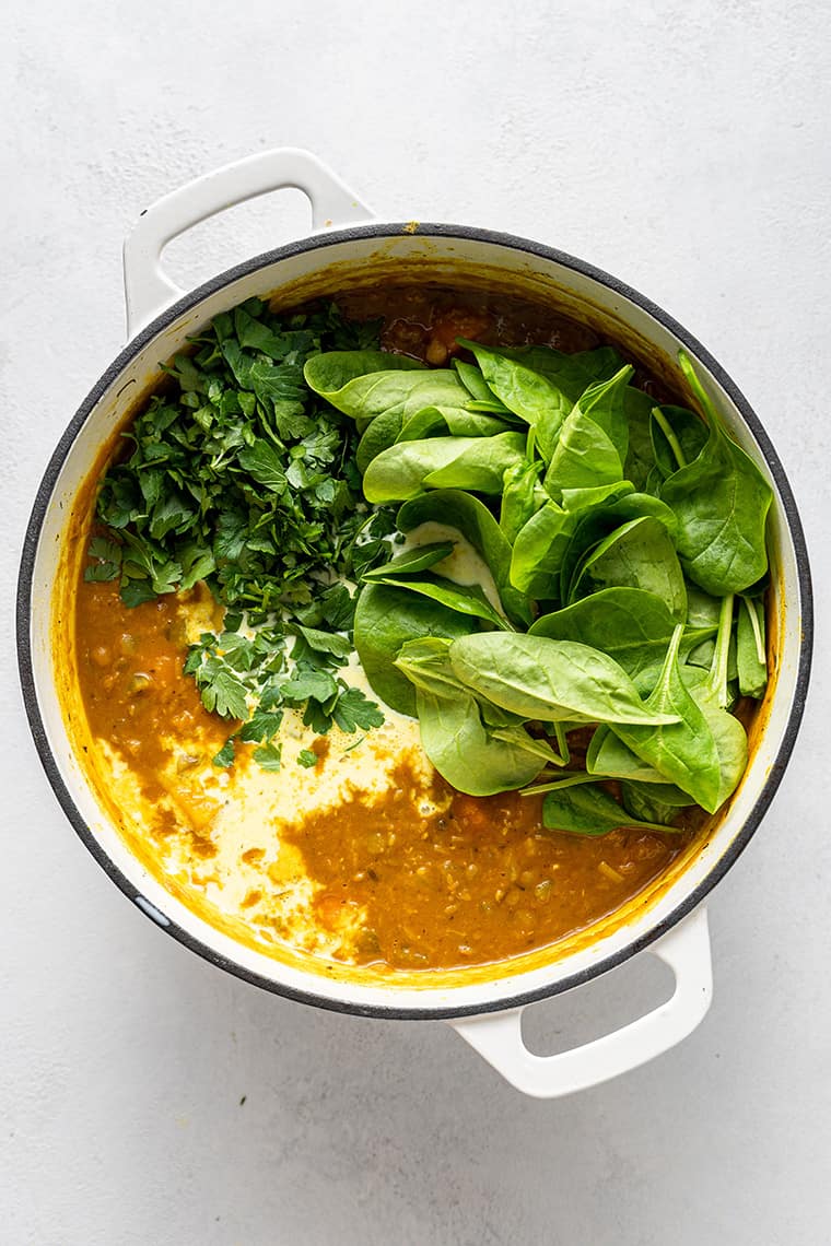 Detox turmeric lentil soup with spinach and parsley on top, before stirring