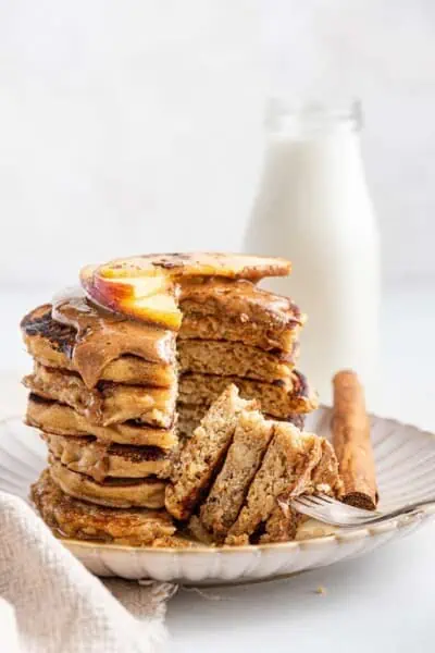 Stack of gluten-free pancakes topped with almond butter and apples