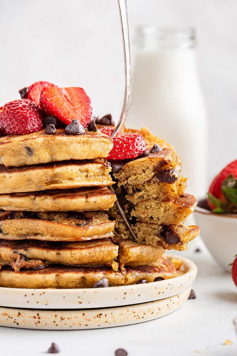 Tall stack of fluffy gluten-free pancakes topped with berries and chocolate chips