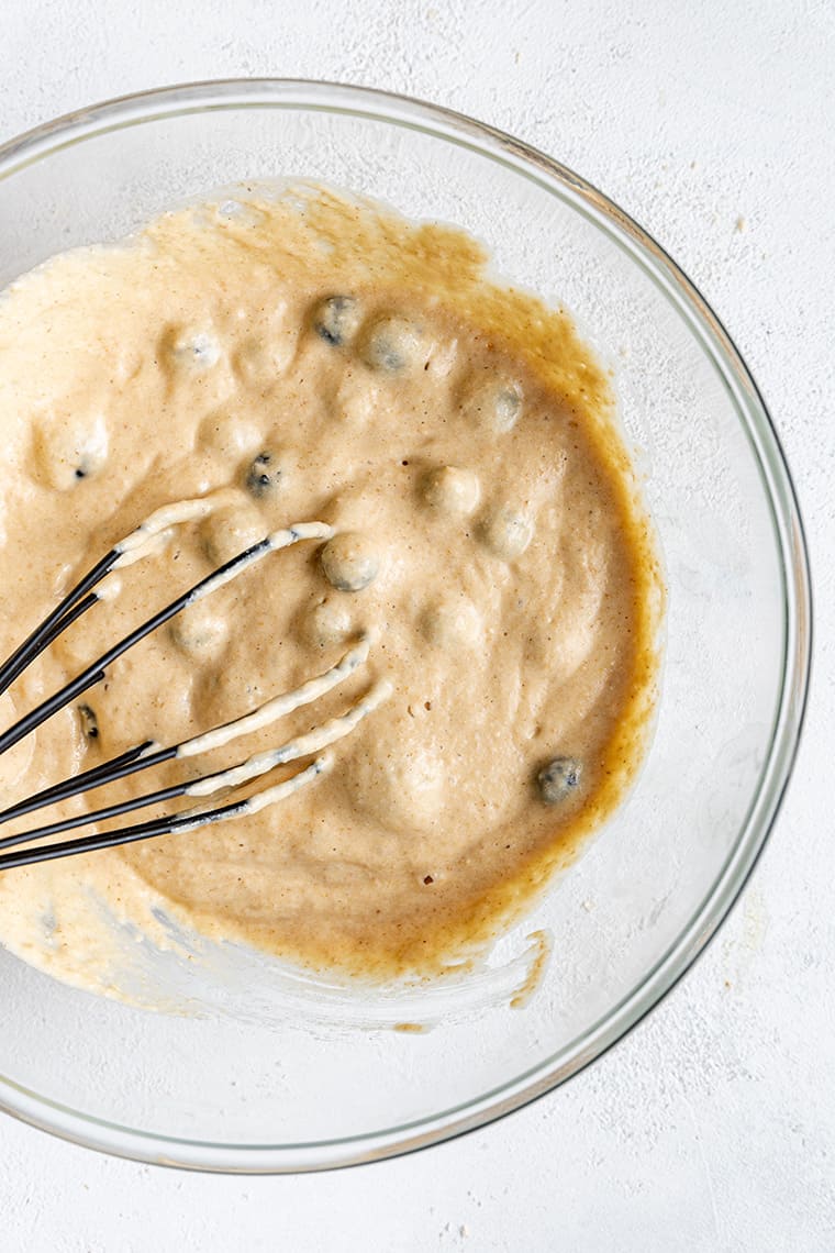 Overhead view of blueberries being whisked into gluten-free pancake batter