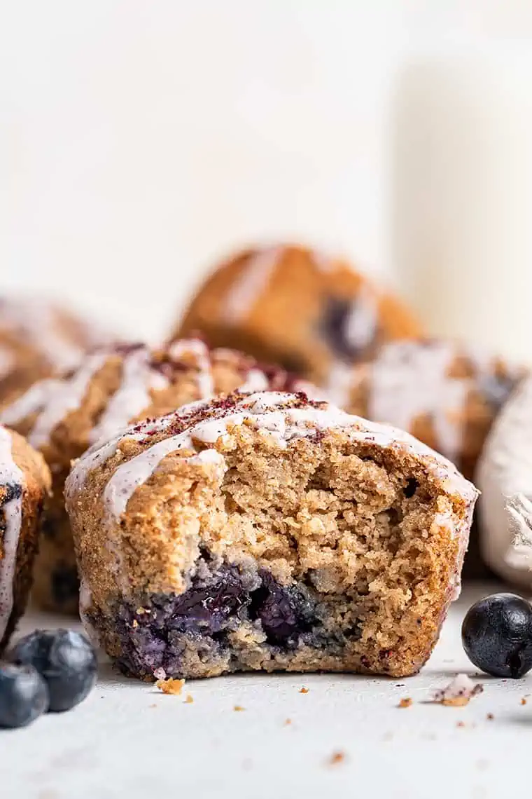 Healthy blueberry muffin with bite taken out to show light, fluffy texture inside