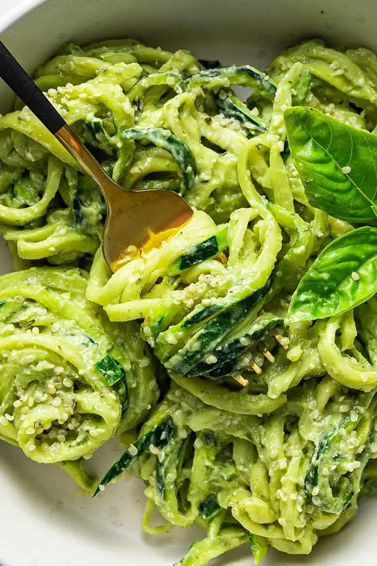 A close-up shot of avocado pesto zucchini noodles swirled around a fork