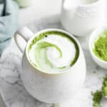 Frothy matcha latte in white mug