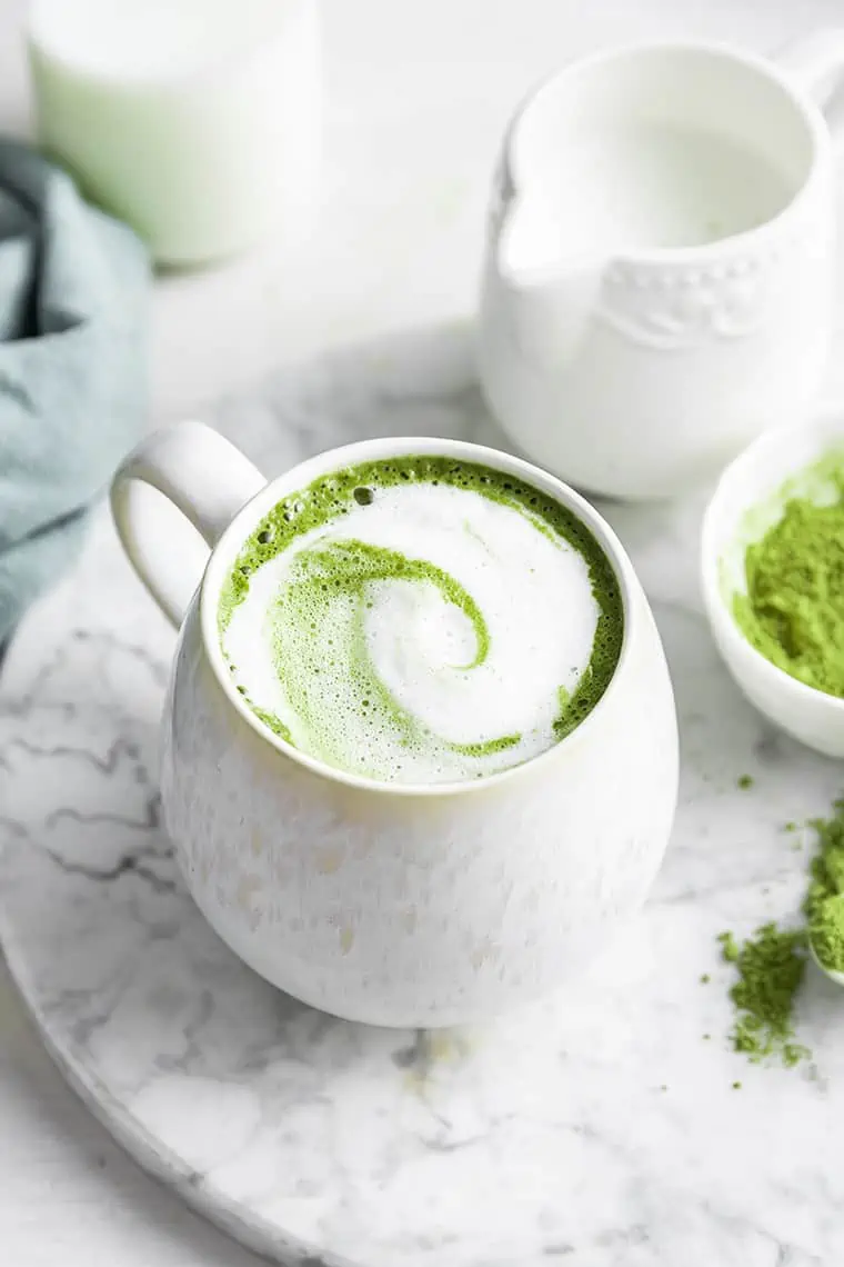 Frothy matcha latte in white mug