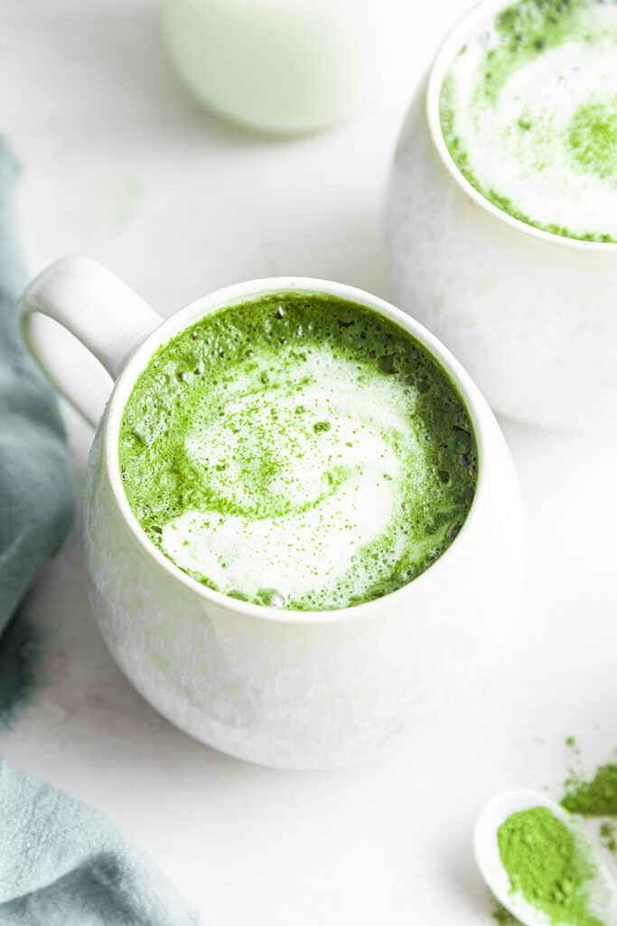 Two mugs of frothy matcha latte