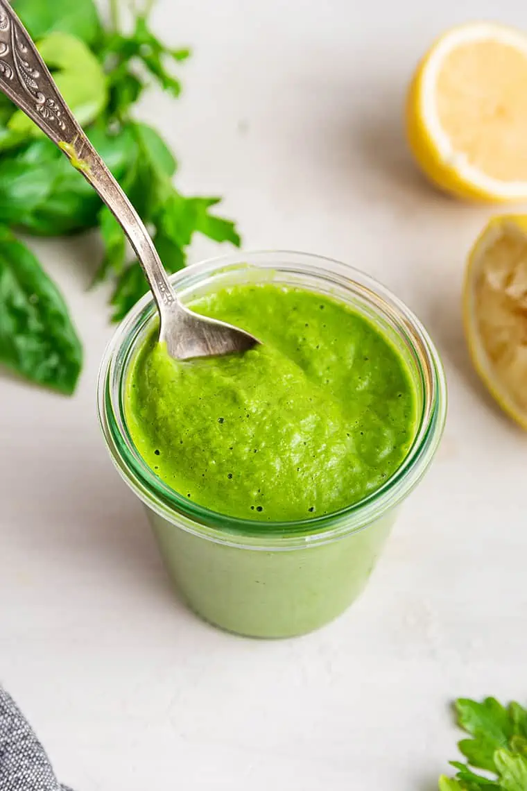 Jar of vegan green goddess salad dressing with spoon