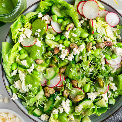 Green goddess salad in serving bowl with dressing and feta