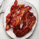 A white oval plate with a pile of cooked bacon on it