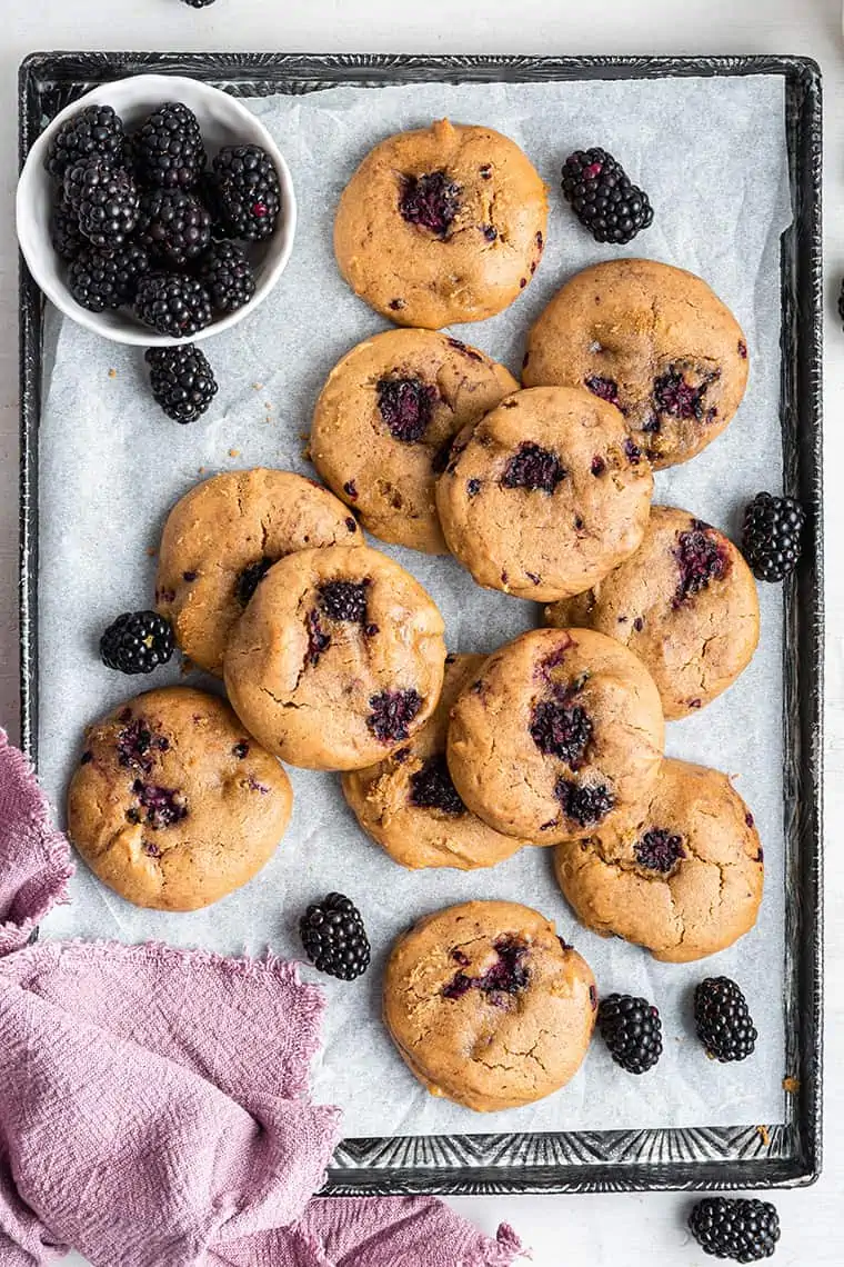 Overhead view of blackberry cookies on baking sheet with fresh berries