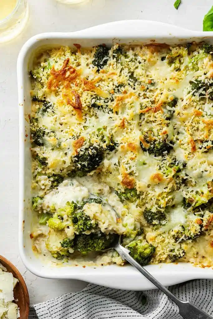 A baking dish of broccoli casserole with a spoon in it