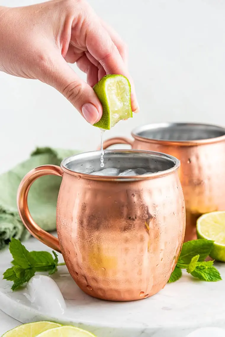 Hand squeezing lime juice into Mexican mule
