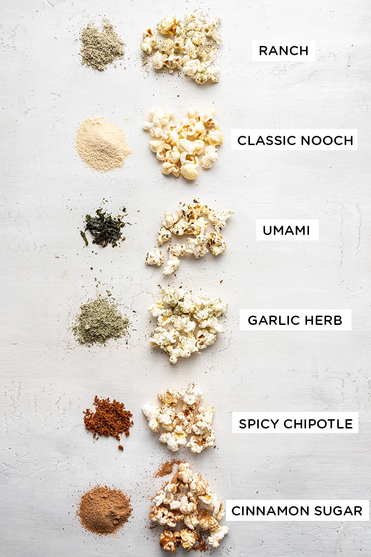 Learn how to make 6 easy popcorn seasonings—sweet, savory, and spicy! Take your popcorn to the next level while still keeping it healthy. Overhead view of popcorn seasonings and popcorn with labels