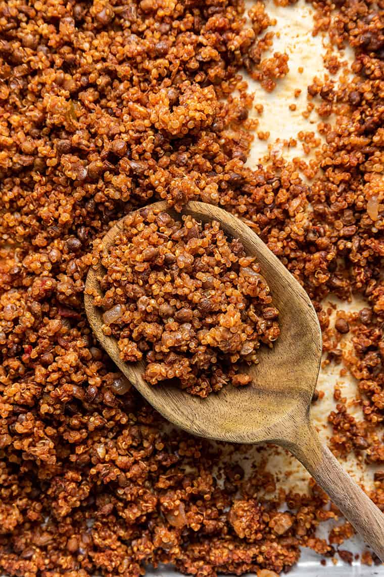 This easy vegan taco meat is made with lentils and quinoa. Unbelievably delicious, super healthy, and ideal for meal prep! Wooden spoon scooping vegan taco meat from sheet pan