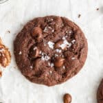 Overhead view of a single espresso cookie, topped with flaky salt, surrounded by espresso beans