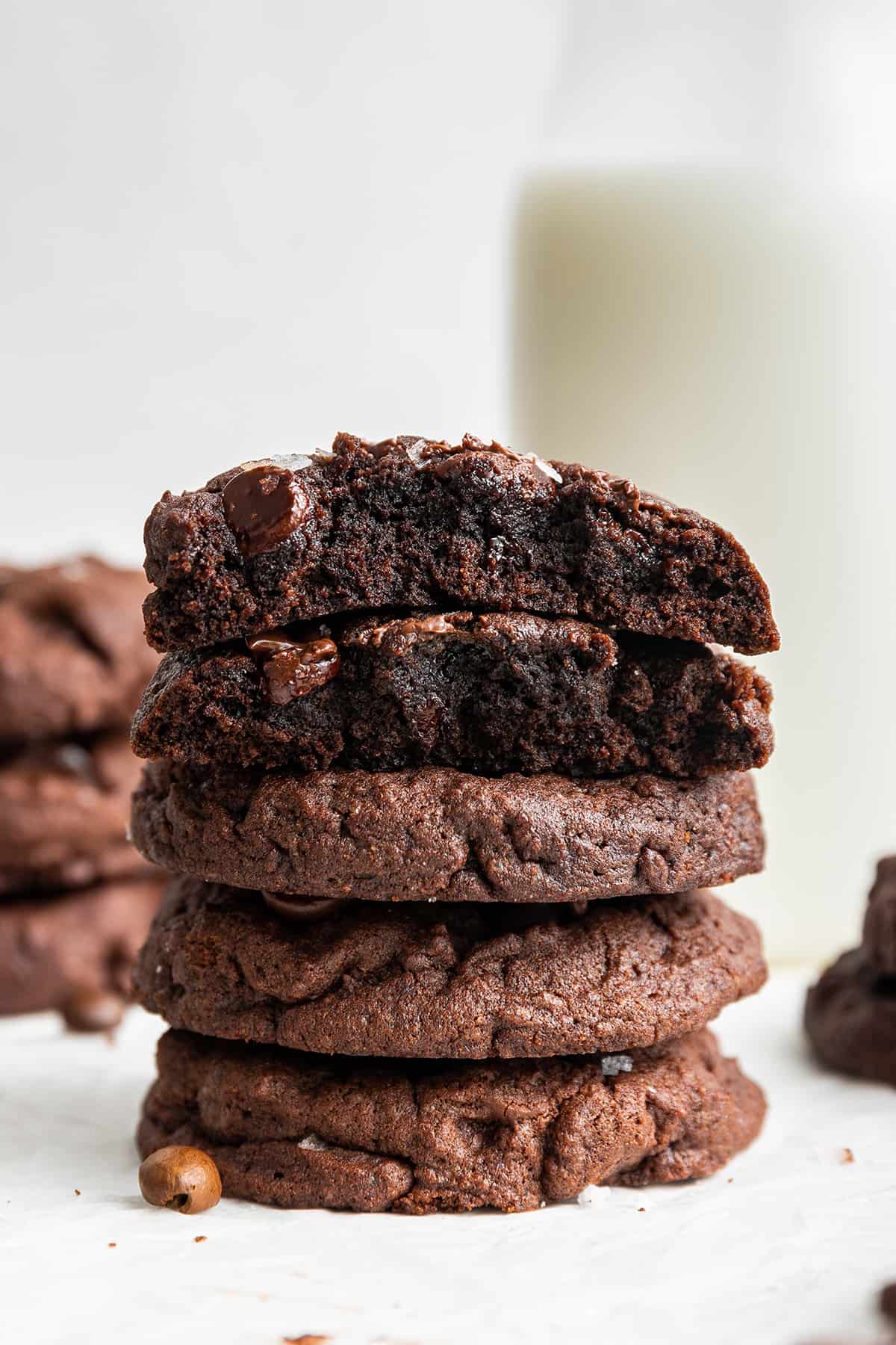 These dairy-free espresso cookies are chewy, packed with chocolate and espresso flavor, and topped with the perfect touch of finishing salt. Even better, it only takes about 20 minutes to make! A stack of five espresso cookies on top of each other, with the top two torn in half