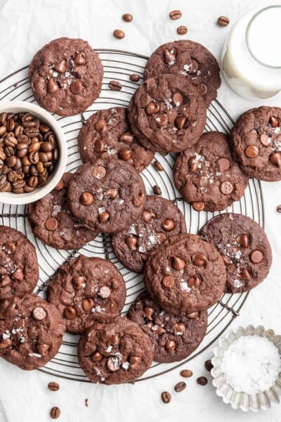 A circular wire rack filled with espresso cookies, next to a bowl of espresso beans