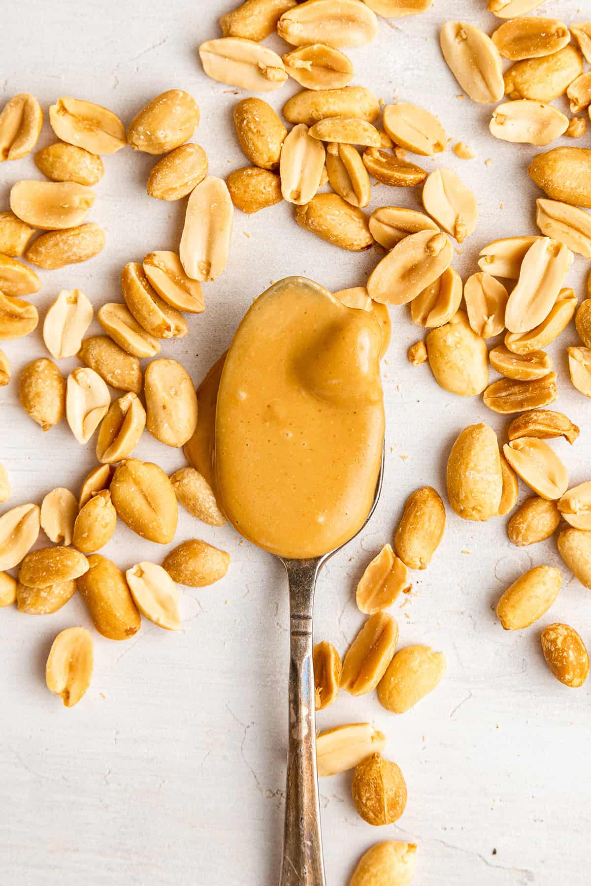 A spoonful of honey roasted peanut butter surrounded by peanutes