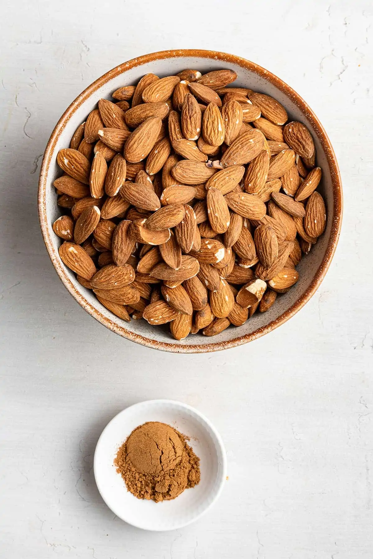 Overhead view of a bowl of almonds next to a bowl of pumpkin spice mix
