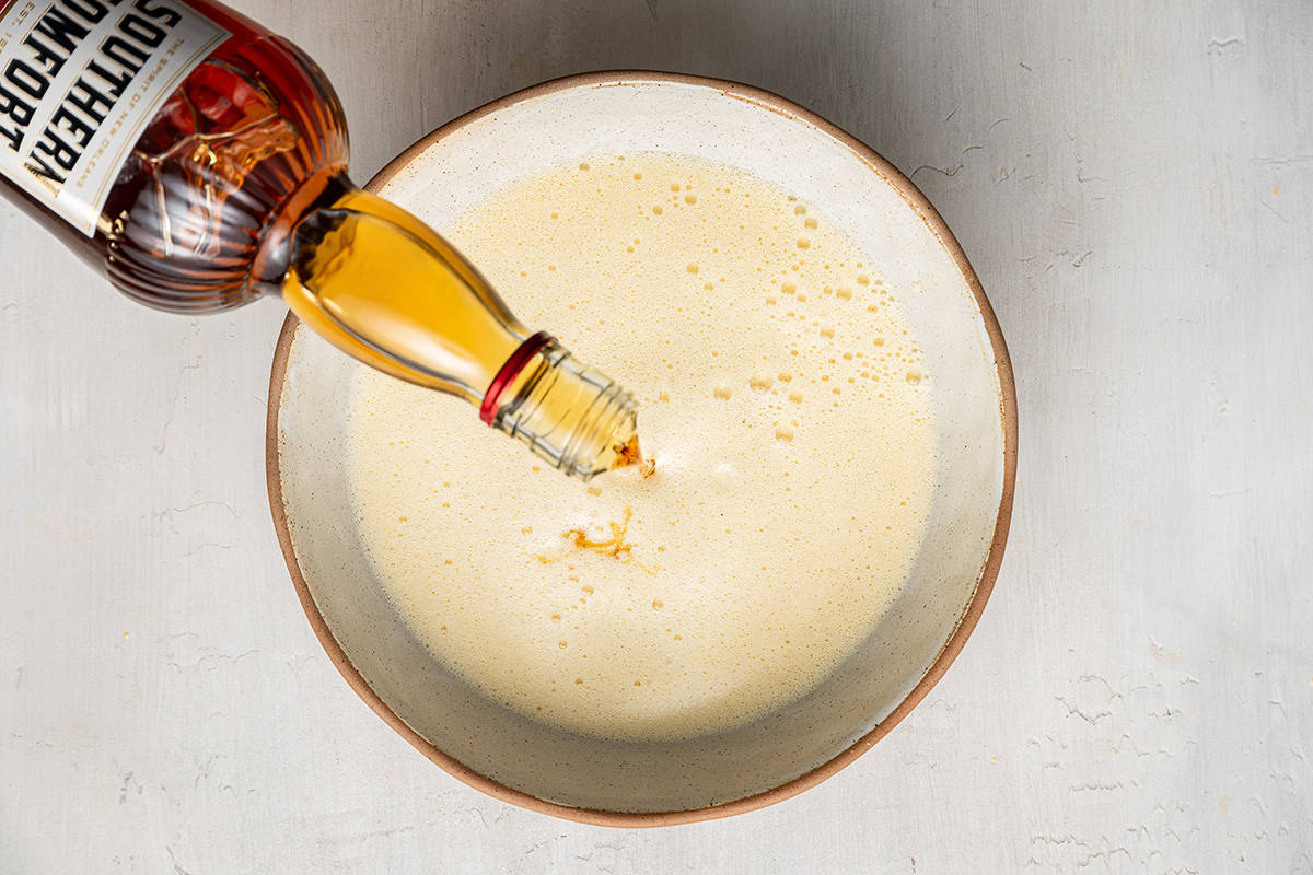 A bottle of Southern Comfort being poured into a bowl of eggnog