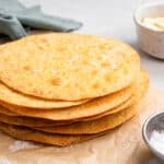 A stack of tostada shells on a sheet of parchment paper.