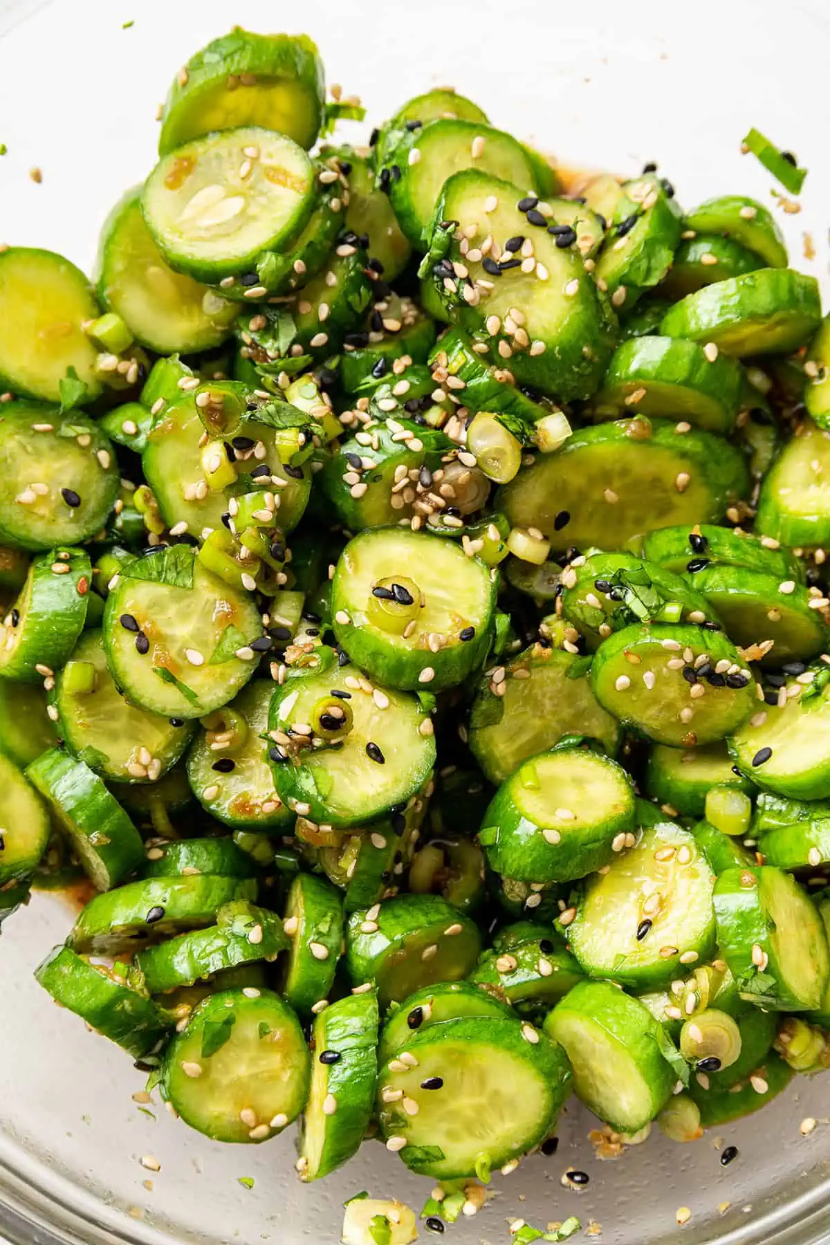 Close up of cucumber salad coated in sesame seeds in a mixing bowl