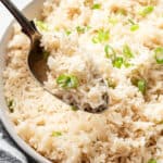 A spoonful of coconut rice with a serving bowl of it in the background.