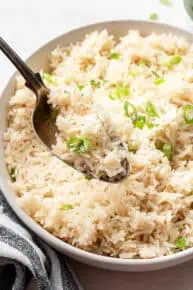 A spoonful of coconut rice with a serving bowl of it in the background.