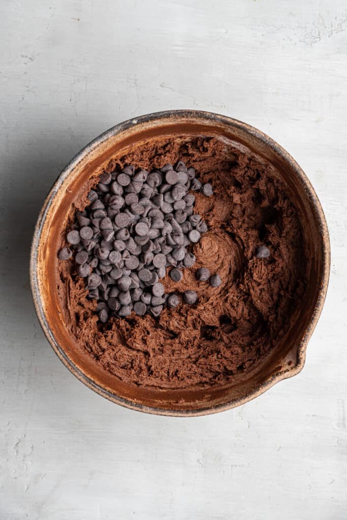 These dairy-free espresso cookies are chewy, packed with chocolate and espresso flavor, and topped with the perfect touch of finishing salt. Even better, it only takes about 20 minutes to make! A mixing bowl with espresso cookie dough, with chocolate chips on top.