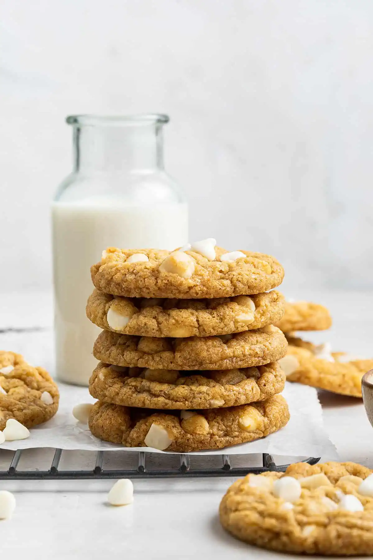 A stack of five cookies with a jar of milk in the background