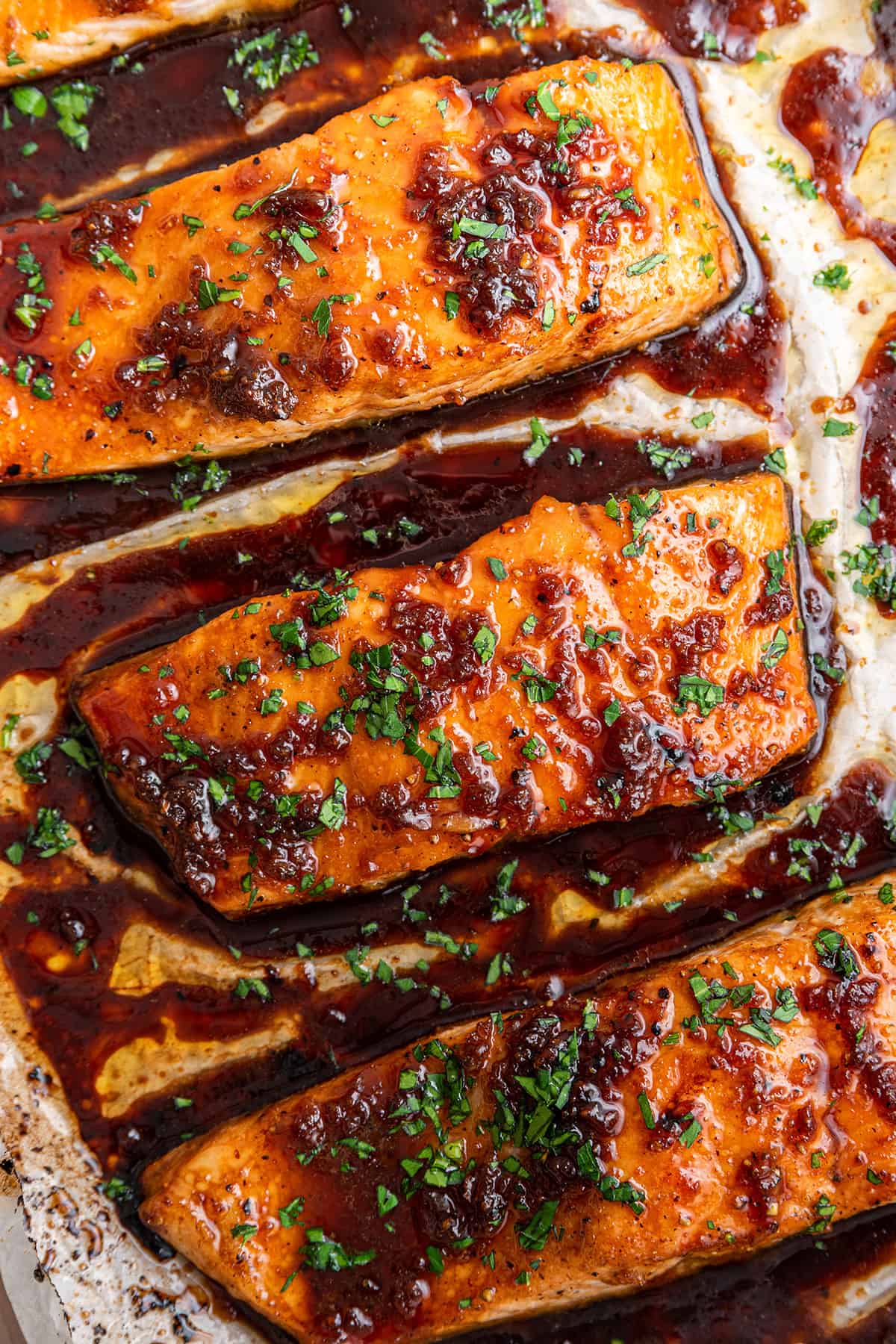 Overhead view of three honey glazed salmon fillets on a baking sheet