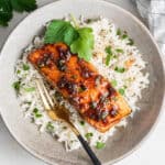 Overhead view of a fillet of honey glazed salmon on top of a bed of cilantro rice, with a fork