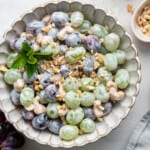 Overhead view of a bowl of salad with red grapes, green grapes, cashews, and yogurt