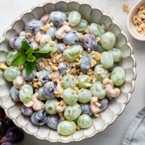 Overhead view of a bowl of salad with red grapes, green grapes, cashews, and yogurt