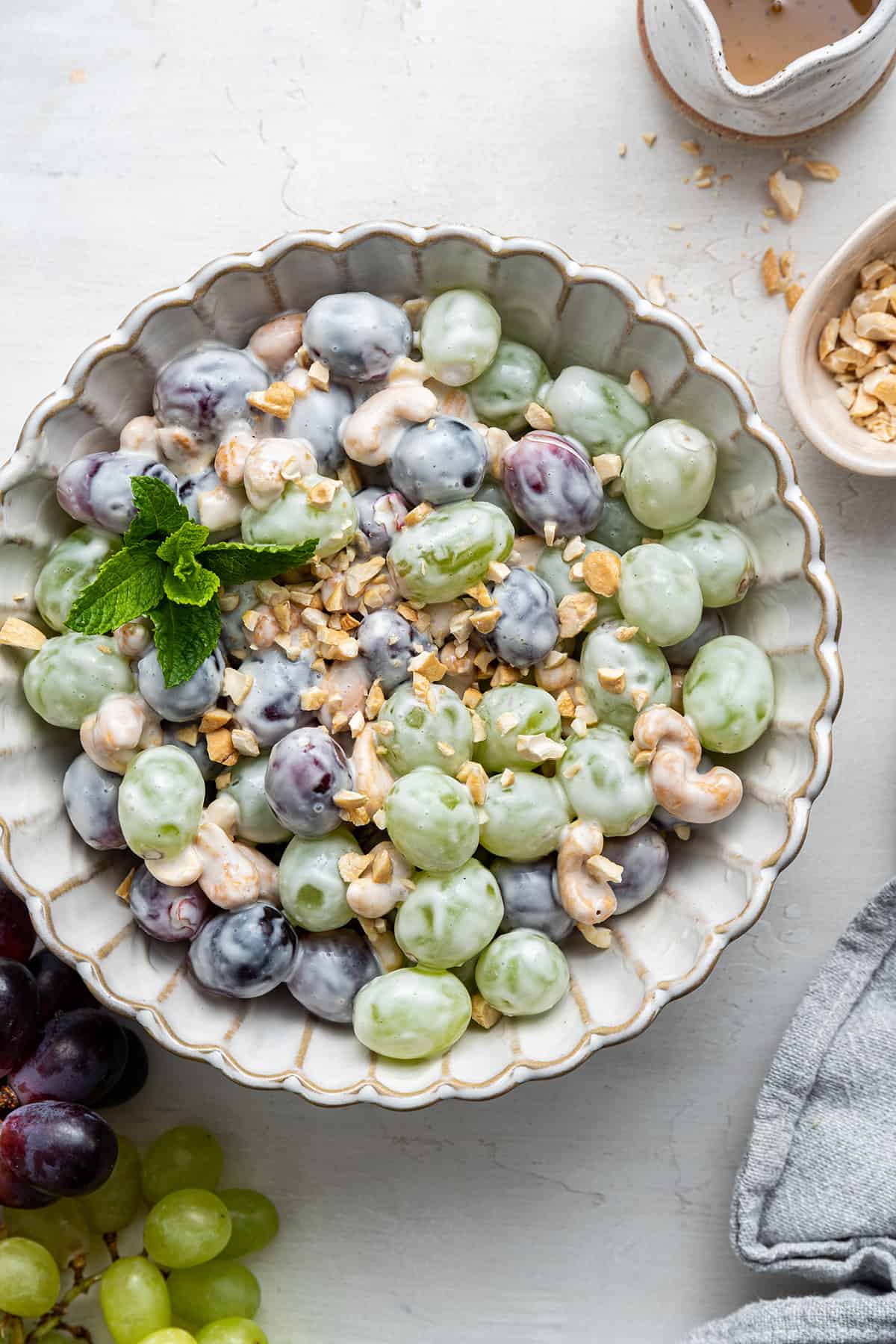 Overhead view of a bowl of salad with red grapes, green grapes, cashews, and yogurt