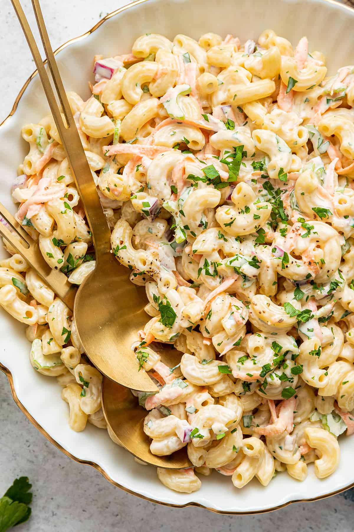 Overhead view of Hawaiian mac salad in serving bowl with two gold serving spoons